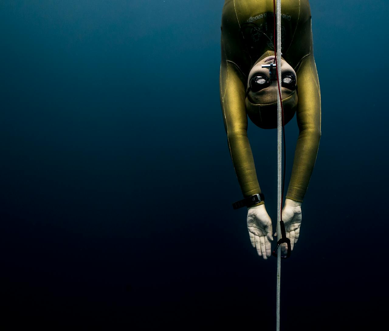 Freediver descending underwater along a guide rope